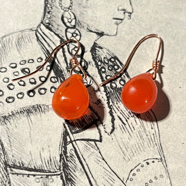 Orange earrings with a black and white illustration in the background