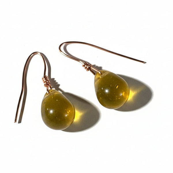 gold amber color teardrop earrings on a textured surface with black and white design