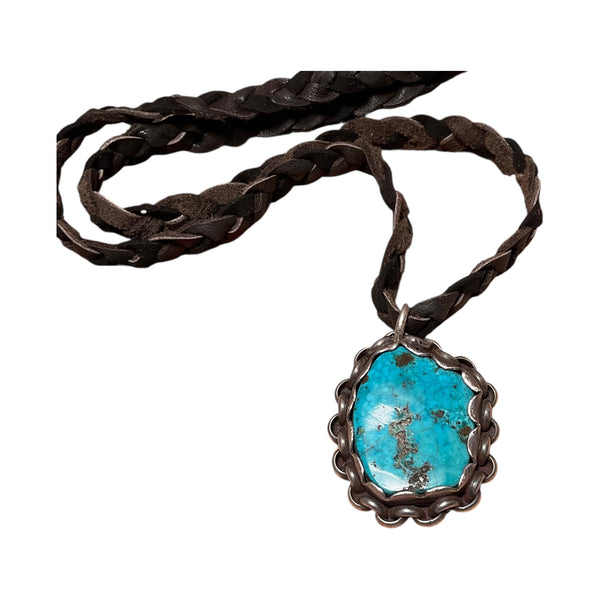 Turquoise pendant necklace on a braided leather cord against a white background