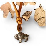 Bronze bull charm on a leather cord with dried leaves in the background