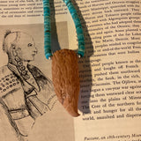 Necklace with wooden pendant and blue beads on a book page