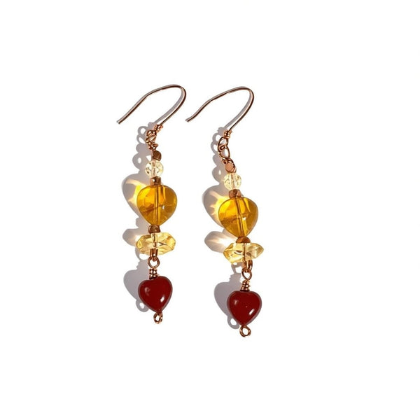 Pair of earrings with yellow and red beads on a white background