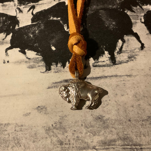 Bison charm on a leather cord with a vintage-style background of bison.