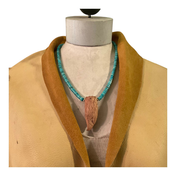 Mannequin wearing a beige coat with a turquoise necklace featuring a wooden pendant.