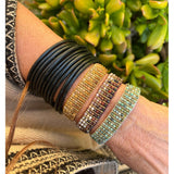 wrist with bracelet and green plants in background
