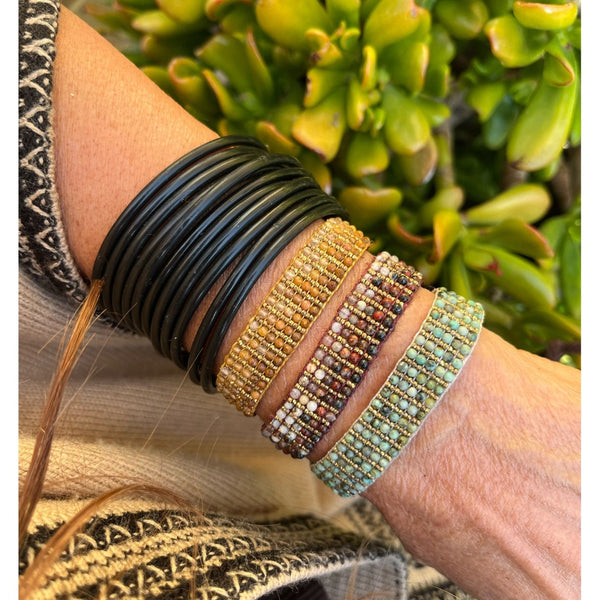 wrist with bracelet and green plants in background